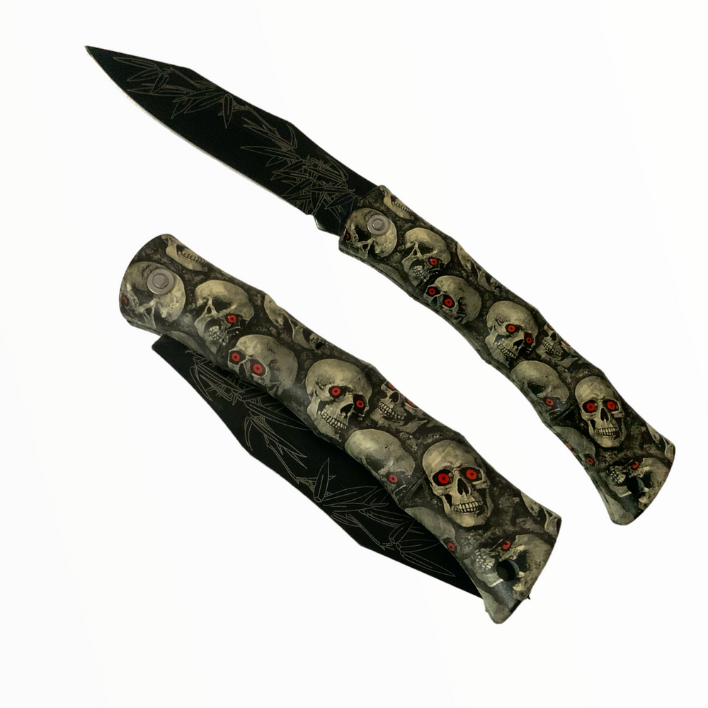 Navaja plegable con hoja metálica y mango de plástico con diseño de calavera